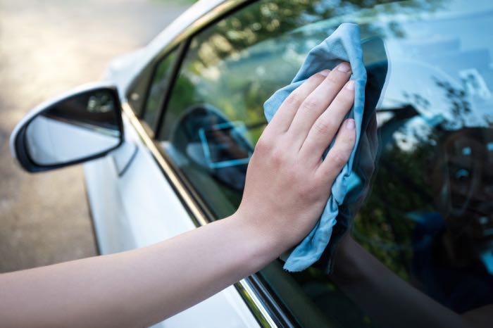 Čištění skla automobilu dolešťovací utěrkou 